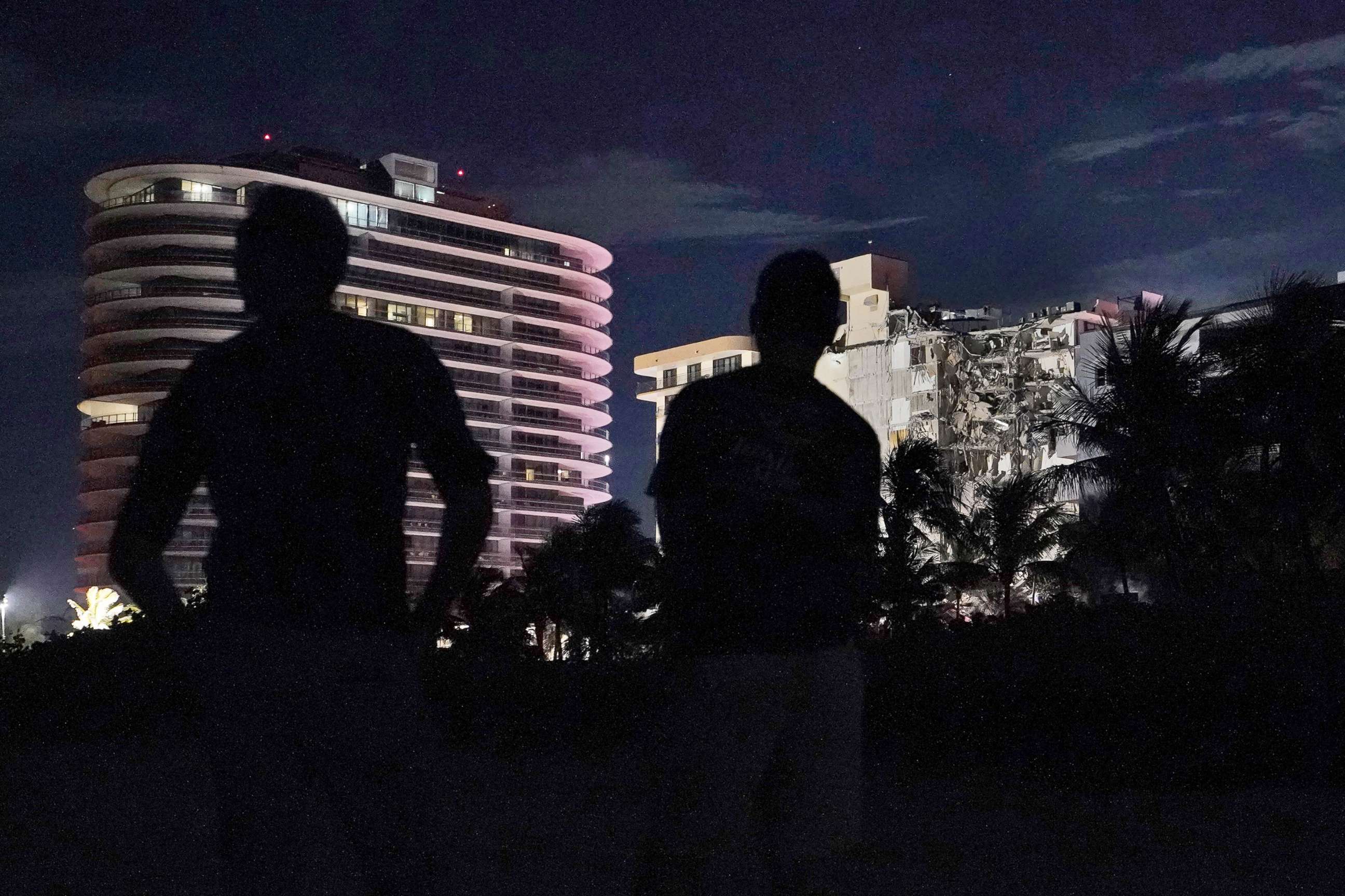 PHOTO: People look at the partially collapsed condo building in the early hours of June 24, 2021, in the Surfside area of Miami, Fla.