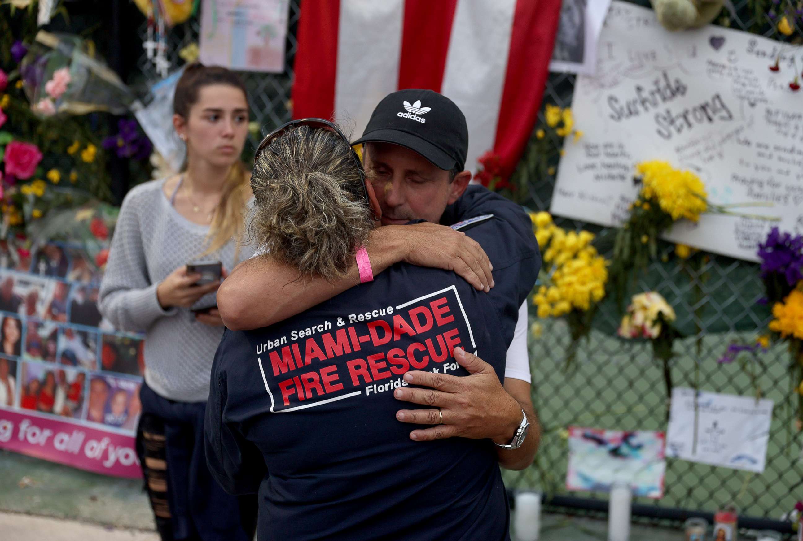 PHOTO: Search and Rescue personnel Maggie Castro hugs Pablo Langesfeld as they visit the memorial to the victims in the collapsed 12-story Champlain Towers South condo building, July 7, 2021, in Surfside, Fla.