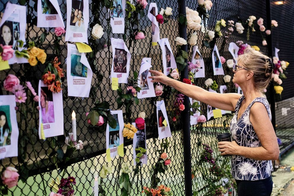 PHOTO: A woman looks at fliers of those thought missing in the collapse of the Champlain Towers South condominium complex in Surfside, Fla., June 26, 2021.