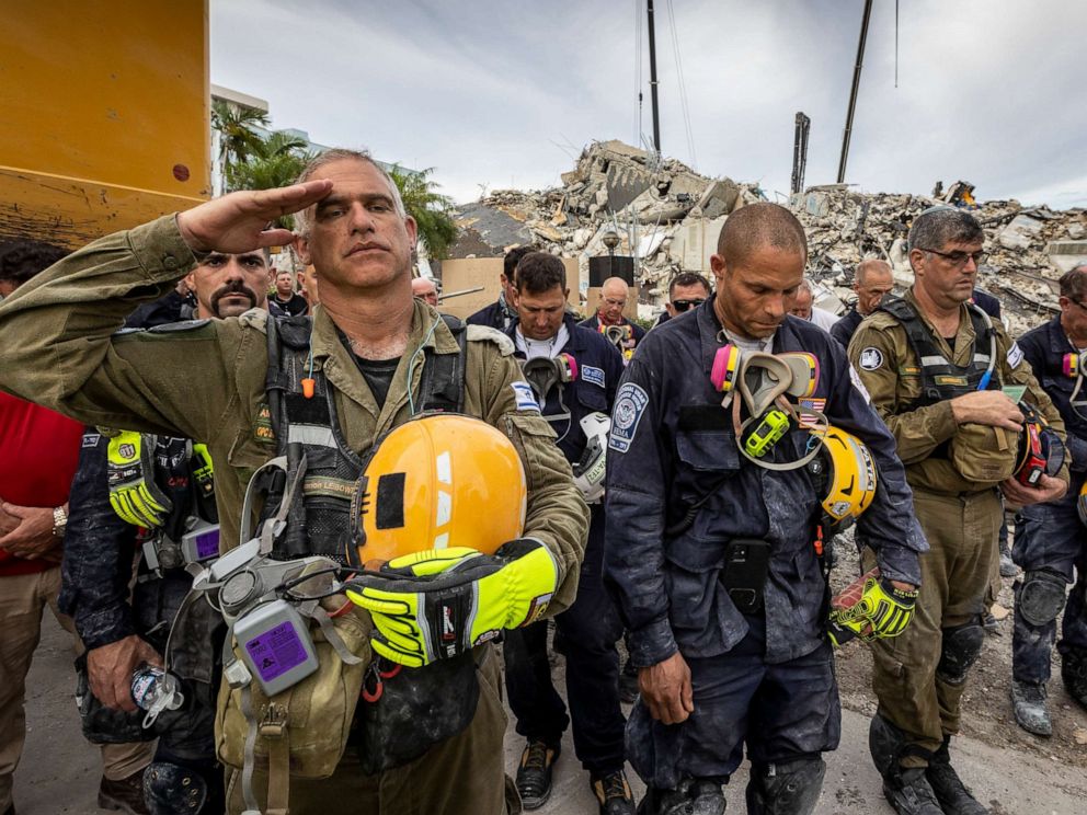 PHOTO: A member of the Israeli search and rescue team, left, salutes in front of the rubble that once was Champlain Towers South during a prayer ceremony, Wednesday, July 7, 2021, in Surfside, Fla. 