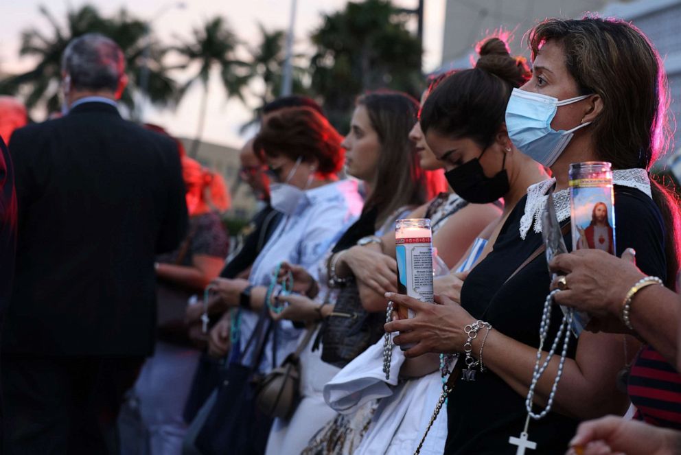 PHOTO: People gather at the memorial site for victims of the collapsed 12-story Champlain Towers South condo building to pray the rosary on July 7, 2021, in Surfside, Fla.