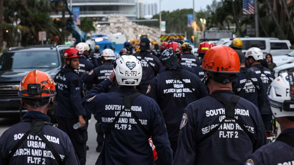 PHOTO: Rescue personnel walk back to work on the recovery operation at the collapsed 12-story Champlain Towers South condo building after a send off for members of the Israel Defense Forces National Rescue Unit, July 10, 2021, in Surfside, Florida.