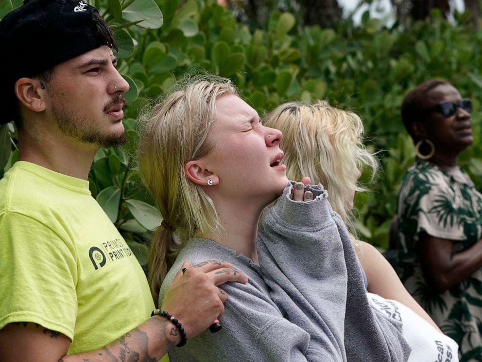 PHOTO: Ariana Hevia, who's mother lives in the building, stands with Sean Wilt, left, near the 12-story beachfront condo building which partially collapsed, as the search for survivors continues, June 25, 2021, in the Surfside area of Miami.