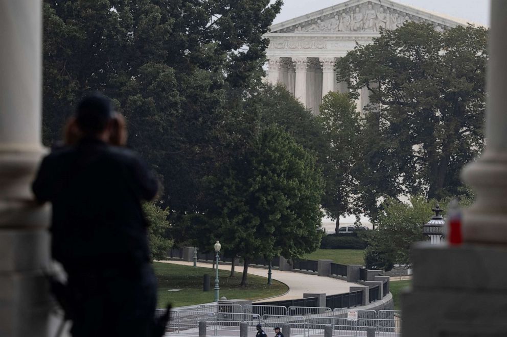 PHOTO: A United States Capitol Police Officer uses binoculars to watch a suspicious vehicle parked in front of the Supreme Court on Oct. 05, 2021, in Washington.