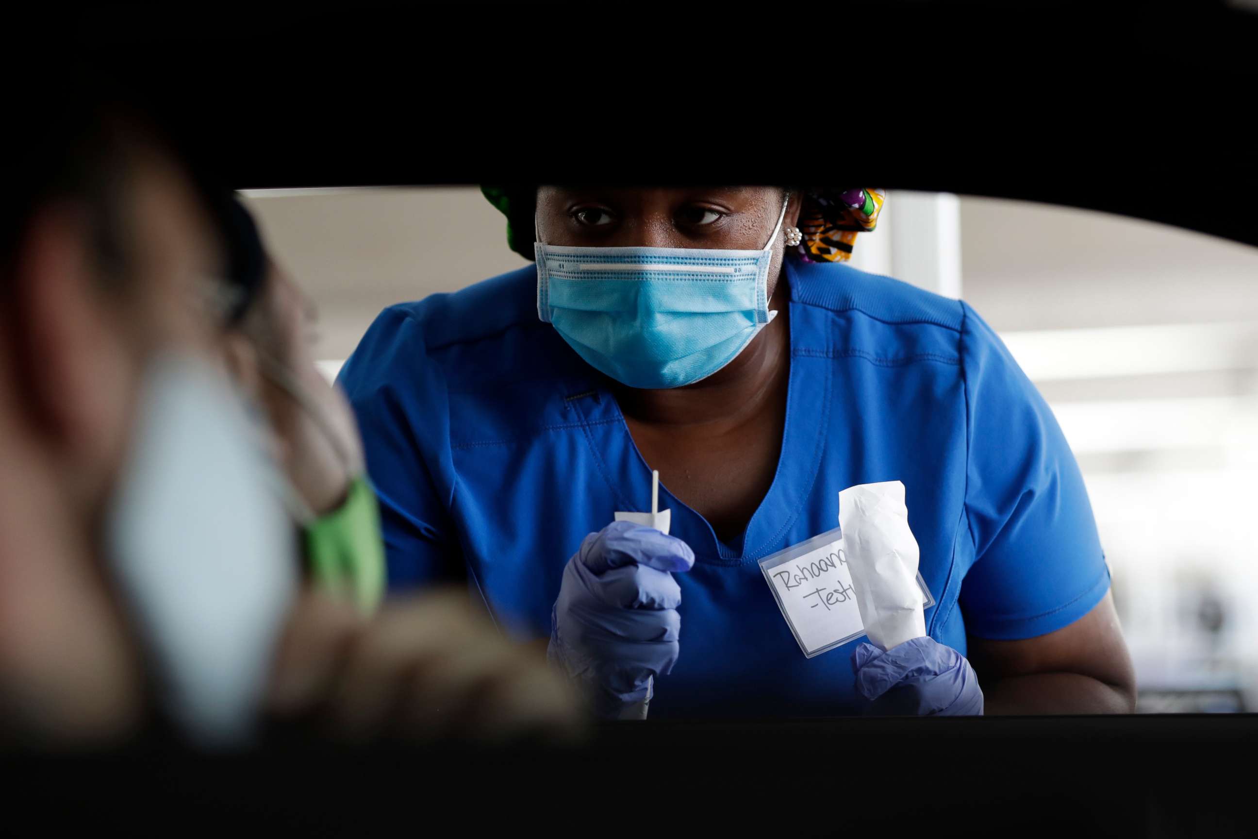 PHOTO: Healthcare worker Rahaana Smith instructs passengers how to use a nasal swab, July 24, 2020, at a drive-thru COVID-19 testing site at the Miami-Dade County Auditorium, in Miami.