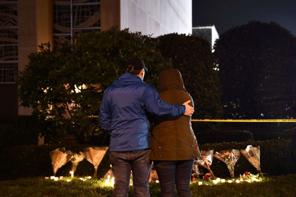 PHOTO: Des gens se tiennent devant des fleurs et des bougies placées sous un cordon de police à l'extérieur de la synagogue Tree of Life après une fusillade mortelle à Pittsburgh, le 27 octobre 2018.