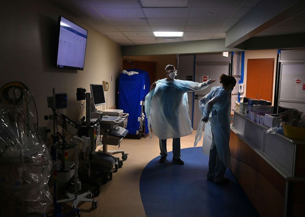 PHOTO: Nurses Brian Gilbert and Stefanie Jimenez suit up with PPE in the Covid-19 section of Tampa General Hospital before entering the ward to work with patients in Tampa, Fla., on Aug. 19, 2020.