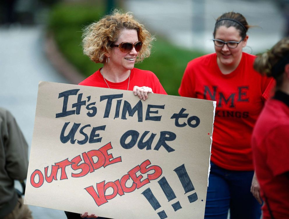 PHOTO: Elizabeth Garlick, a teacher at North Mor Elementary School in Northglenn, Colo., waves a placard during a rally outside the State Capitol, April 16, 2018, in Denver. 