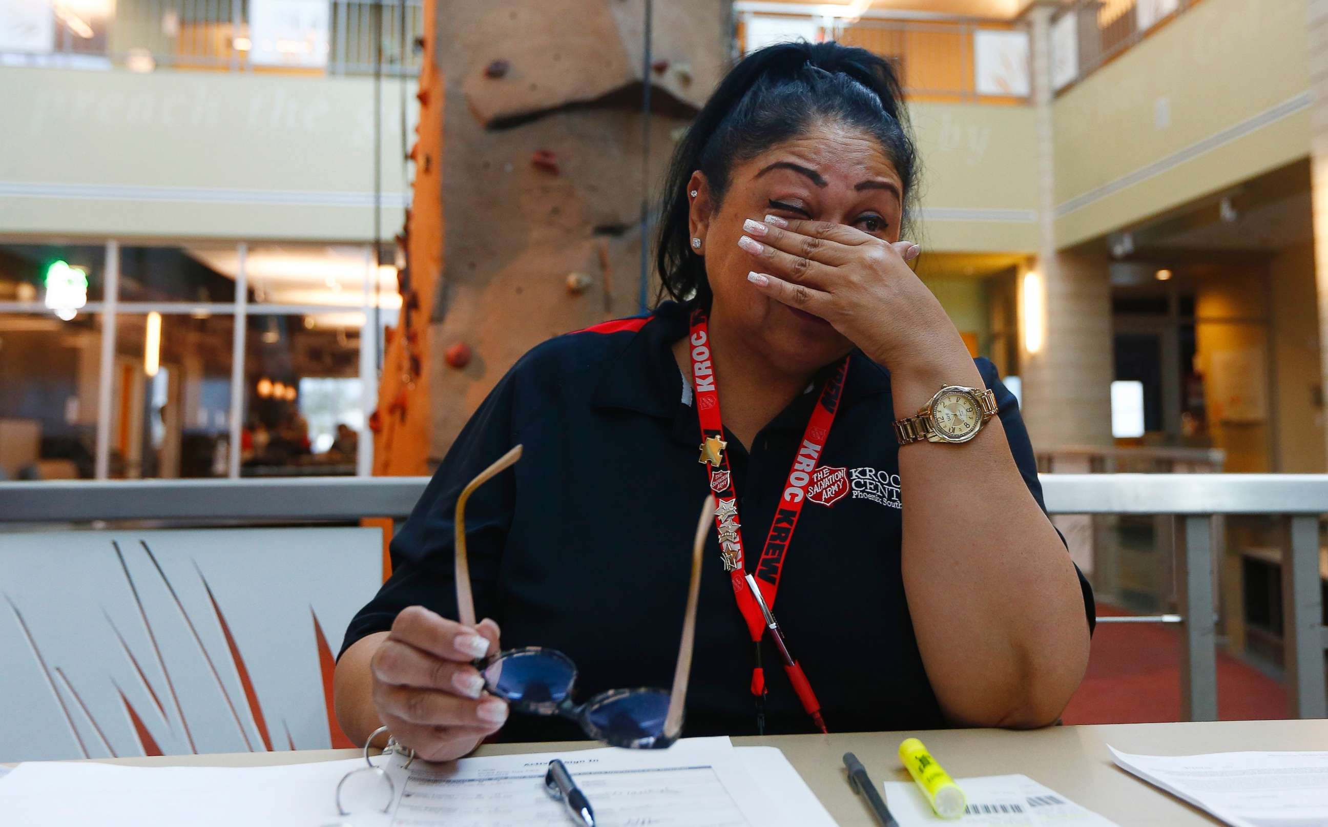 PHOTO: Special education teacher Charmaine Woods wipes away tears as she talks about not being at her teaching job in the Roosevelt School District as she checks kids in at a special day camp at the Salvation Army Kroc Center, April 26, 2018, in Phoenix.