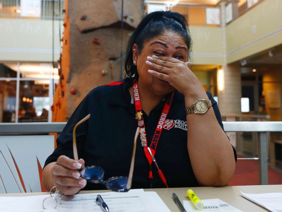 PHOTO: Special education teacher Charmaine Woods wipes away tears as she talks about not being at her teaching job in the Roosevelt School District as she checks kids in at a special day camp at the Salvation Army Kroc Center, April 26, 2018, in Phoenix.