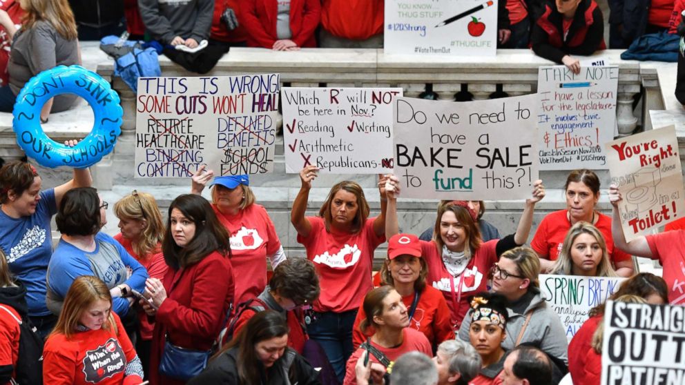 PHOTO: Teachers from across Kentucky hold up signs as they fill the state Capitol to rally for increased funding and to protest last minute changes to their state funded pension system, April 2, 2018, in Frankfort, Ky.