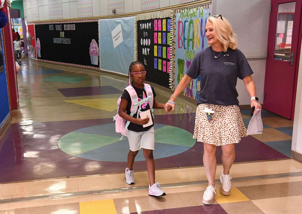 PHOTO: Avery Hill holds hands with art teacher Melony Maughn as she looks for her class while parents and children arrive for the first day of the 2022-23 school year in Tuscaloosa, Ala., Aug. 10, 2022.