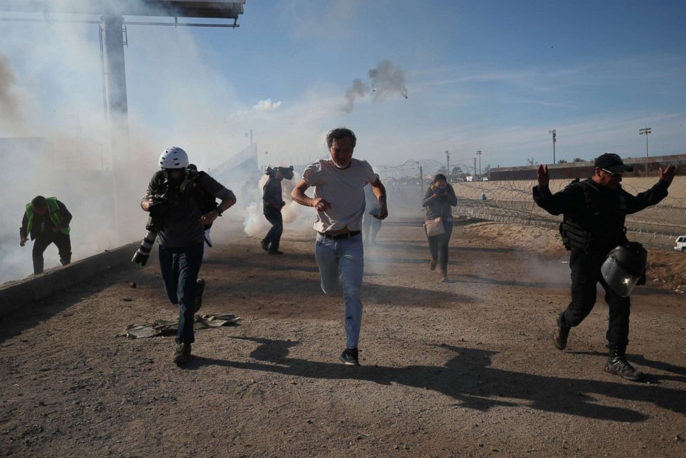 PHOTO: Migrants and members of the media run from tear gas released by U.S border patrol near the fence between Mexico and the United States in Tijuana, Mexico, Nov. 25, 2018. 