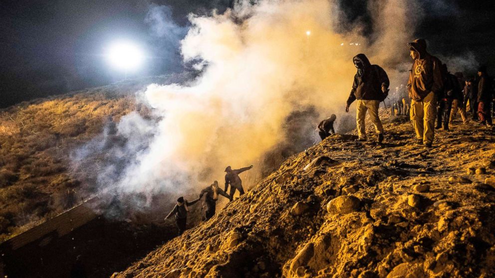 Central American migrants run away from tear gas thrown by the US border patrol, after they tried to cross from Tijuana to San Diego in the US, as seen from Tijuana, Mexico, Jan. 1, 2019.