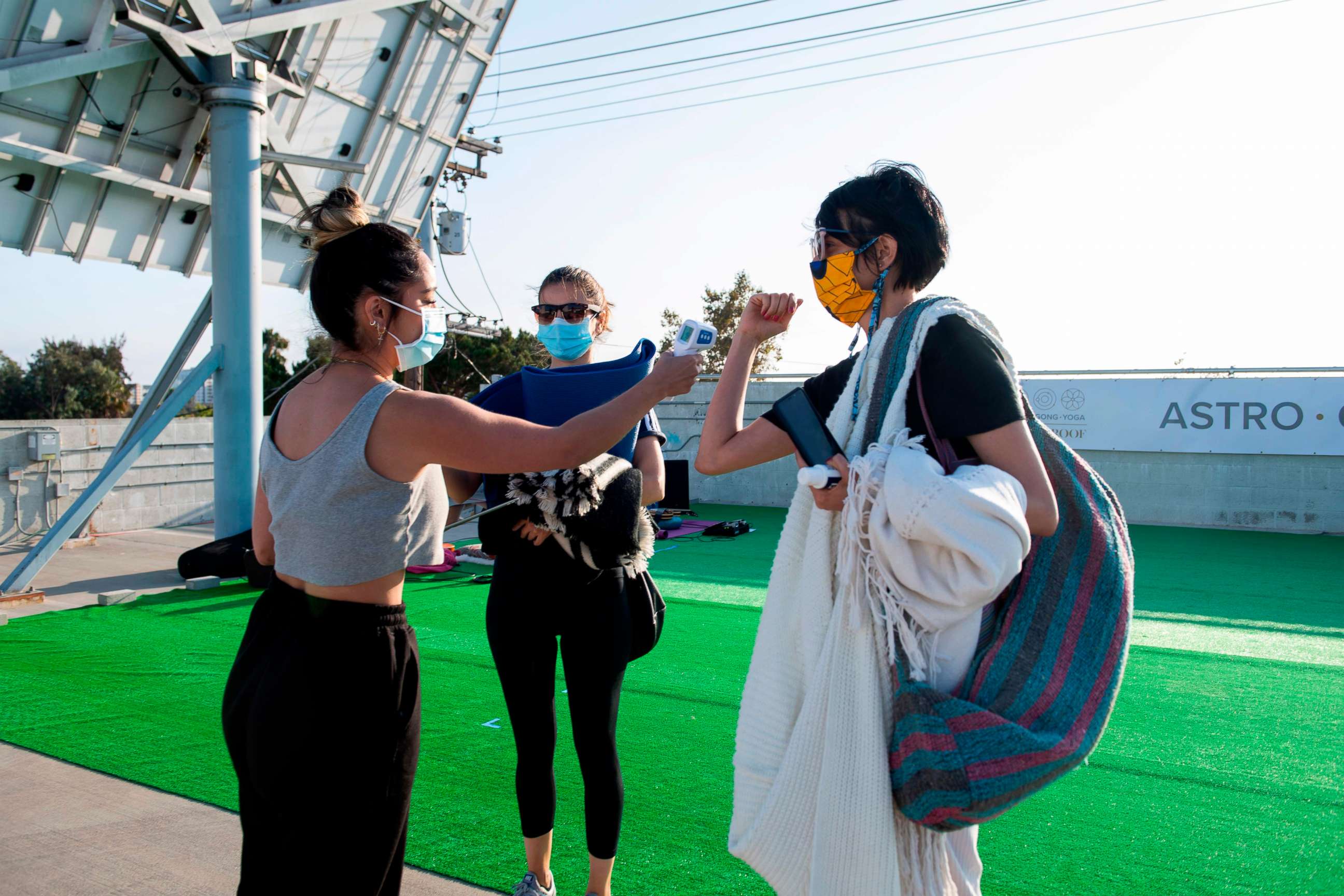 PHOTO: A hostess from Astro Gong Yoga Studio checks a woman's temperature before she attends a yoga class being held on a roof top parking lot, as the studio cannot be open to the public amid the coronavirus pandemic, in Los Angeles on August 4, 2020.