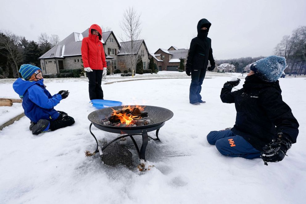 PHOTO: Luke Nolan, right, tosses a snowball at Connor Swyt, left, as neighbors stand around a fire pit on their street, Feb. 15, 2021, in Nolensville, Tenn.