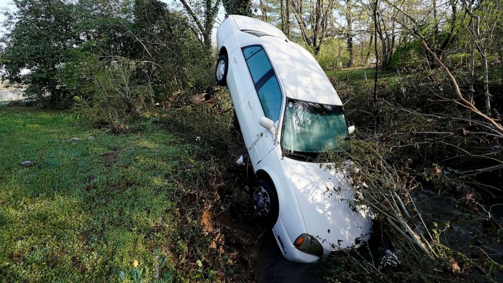 PHOTO: A car that was carried by floodwaters leans against a tree in a creek, March 28, 2021, in Nashville, Tenn.