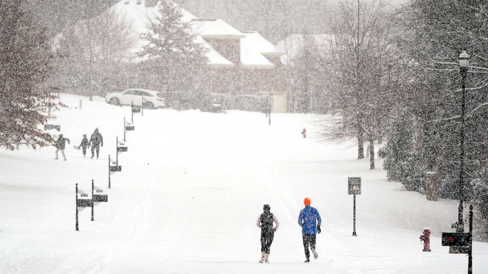 PHOTO: Joggers run down a street as a second winter storm in a week brings more snow, Feb. 18, 2021, in Nolensville, Tenn.