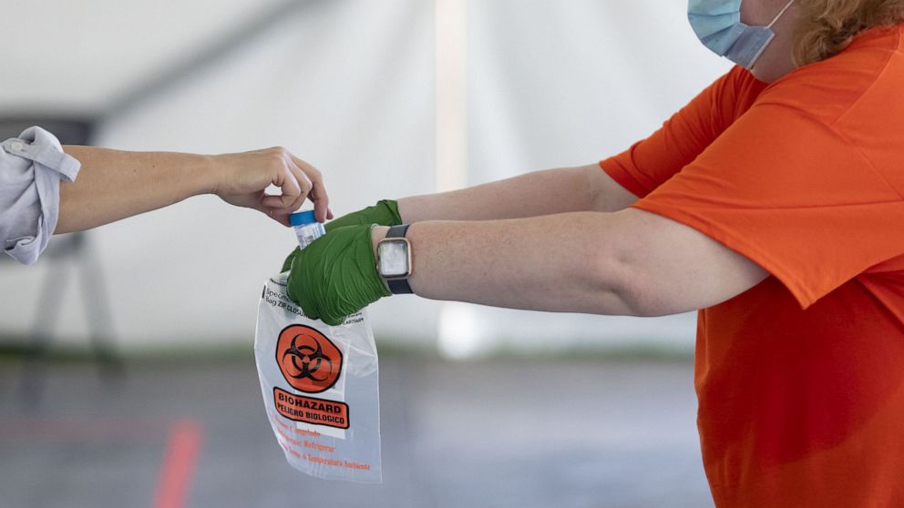PHOTO: A COVID-19 saliva sample is collected as testing is conducted, July 7, 2020, in a tent on the University of Illinois at Urbana-Champaign campus.