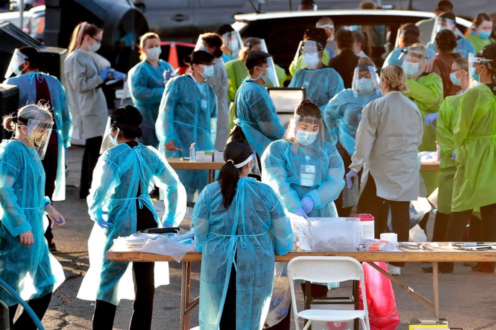 PHOTO: Medical personnel prepare to test hundreds of people lined up in vehicles, June 27, 2020, in Phoenix.