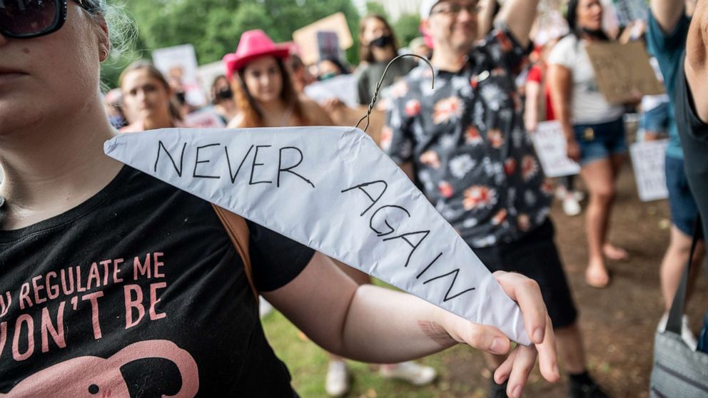 PHOTO: A woman holds a clothes hanger wrapped in paper with "Never again" written on it at a protest for abortion rights outside the Texas state capitol on May 29, 2021, in Austin.