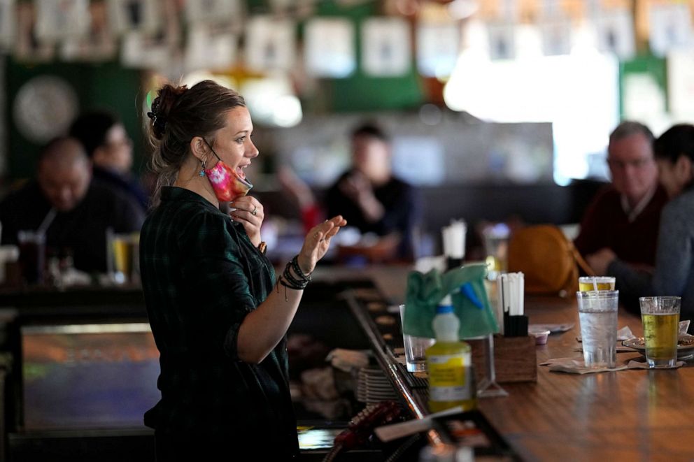 PHOTO: Bartender Alyssa Dooley talks with customers at Mo's Irish Pub, March 2, 2021, in Houston.