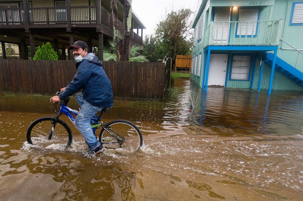PHOTO: Rafael Juarez rides his bicycle through a street flooded by Tropical Storm Beta as he makes his way home from the store, Sept. 21, 2020, in Galveston, Texas.
