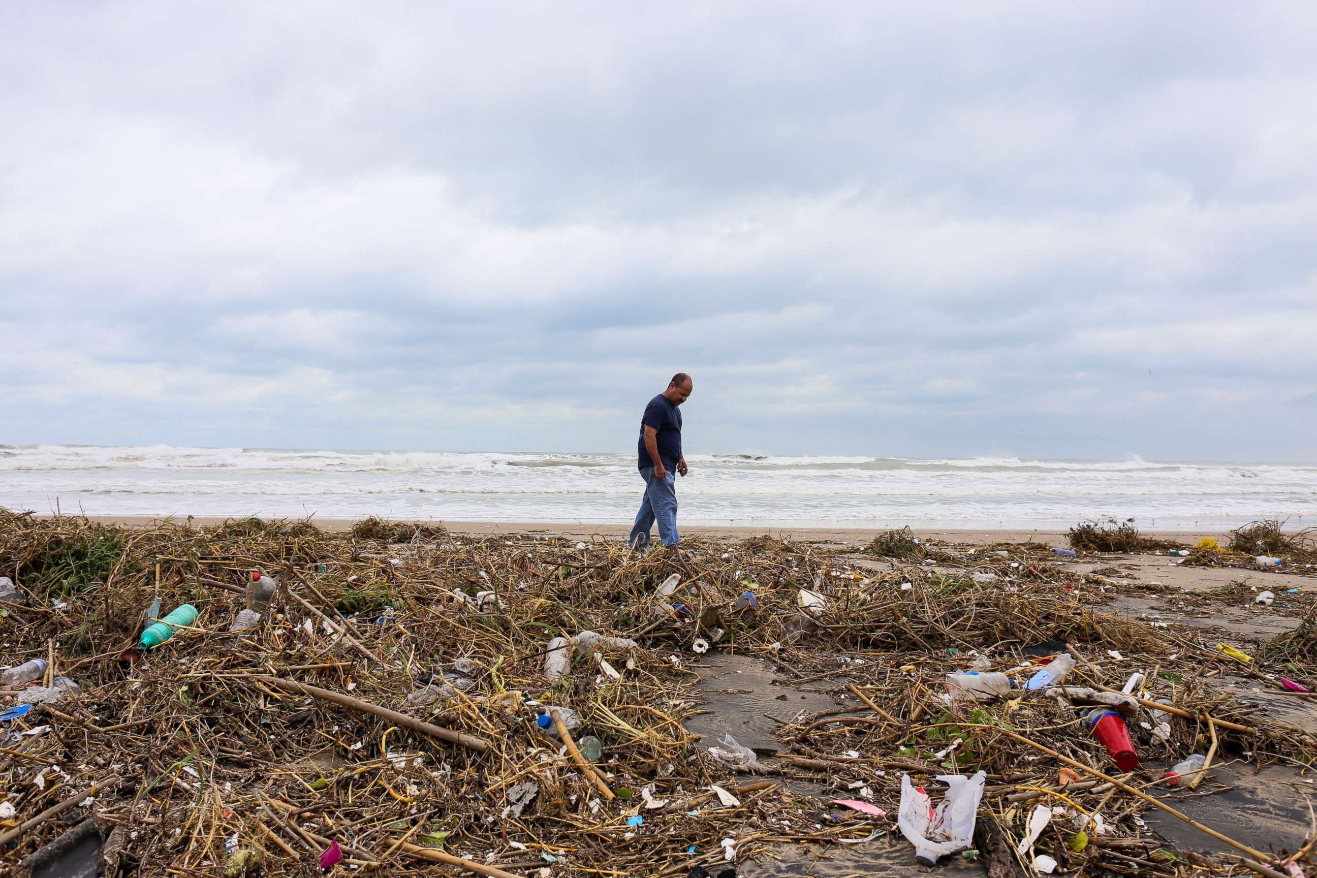 PHOTO: Max Lopez looks for useable items, Sept. 21, 2020, as he walks through piles of trash and debris swept in by outer winds from Tropical Storm Beta over the weekend on Boca Chica Beach outside Brownsville, Texas.