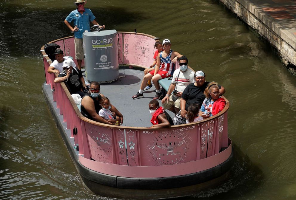 PHOTO: Visitors, some wearing masks to protect against the spread of COVID-19, ride a river barge along the River Walk, July 7, 2020, in San Antonio.