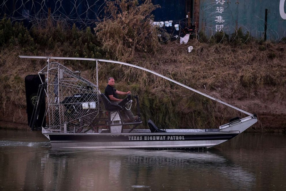 PHOTO: In this July 21, 2023, file photo, a Texas Department of Public Safety officer watches a group of migrants as he navigates on the north side of the Rio Grande.