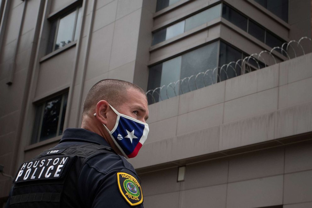 PHOTO: A police officer, wearing a mask with the colors of the Texas flag, stands guard outside China's Consulate after Chinese employees left the building, in Houston, on July 24, 2020.
