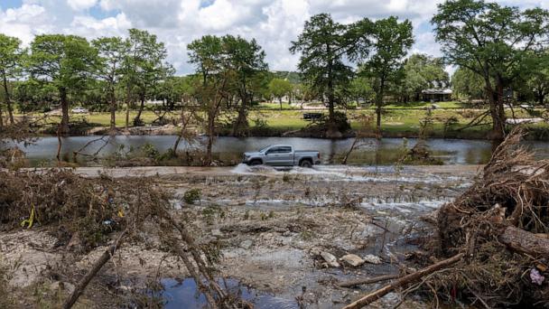 A vehicle drives through a road flooded by the waters of the Guadalupe River, in Hunt, Texas, July 9, 2025.
