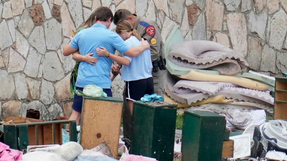 PHOTO: An officer prays with a family as they pick up items at Camp Mystic in Hunt, Texas, July 9, 2025.