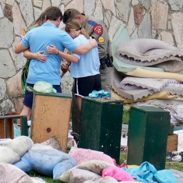 An officer prays with a family as they pick up items at Camp Mystic in Hunt, Texas, July 9, 2025.