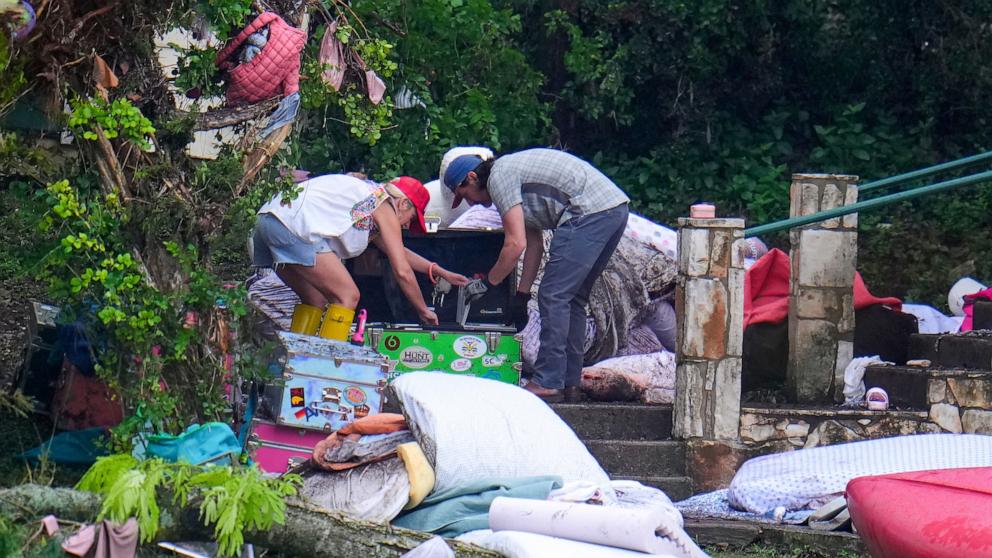 PHOTO: People look through belongings on a camp trunk at Camp Mystic along the banks of the Guadalupe River after a flash flood swept through the area, July 6, 2025, in Hunt, Texas.