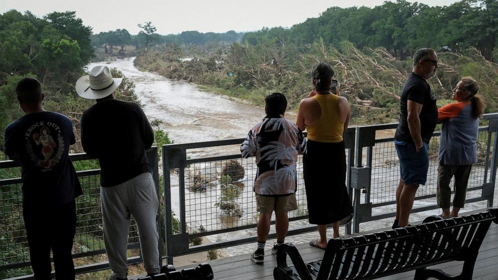 PHOTO: People look at the Guadalupe river, following flash flooding, as they gather after receiving a SMS alerting on potential floods in the area, in Kerrville, Texas, July 6, 2025.