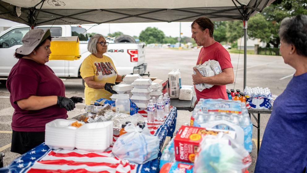 PHOTO: A man grabs supplies from the Rodriguez family of Uvalde in a parking lot in the aftermath of deadly flooding in Kerrville, Texas, July 6, 2025. 
