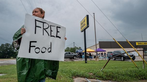 A volunteer displays a sign for free food for people in need of relief, July 6, 2025 in Center Point, Texas