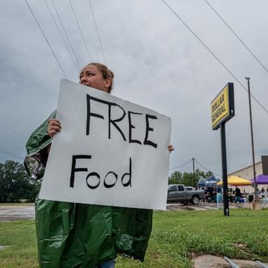 PHOTO: A volunteer displays a sign for free food for people in need of relief, July 6, 2025 in Center Point, Texas