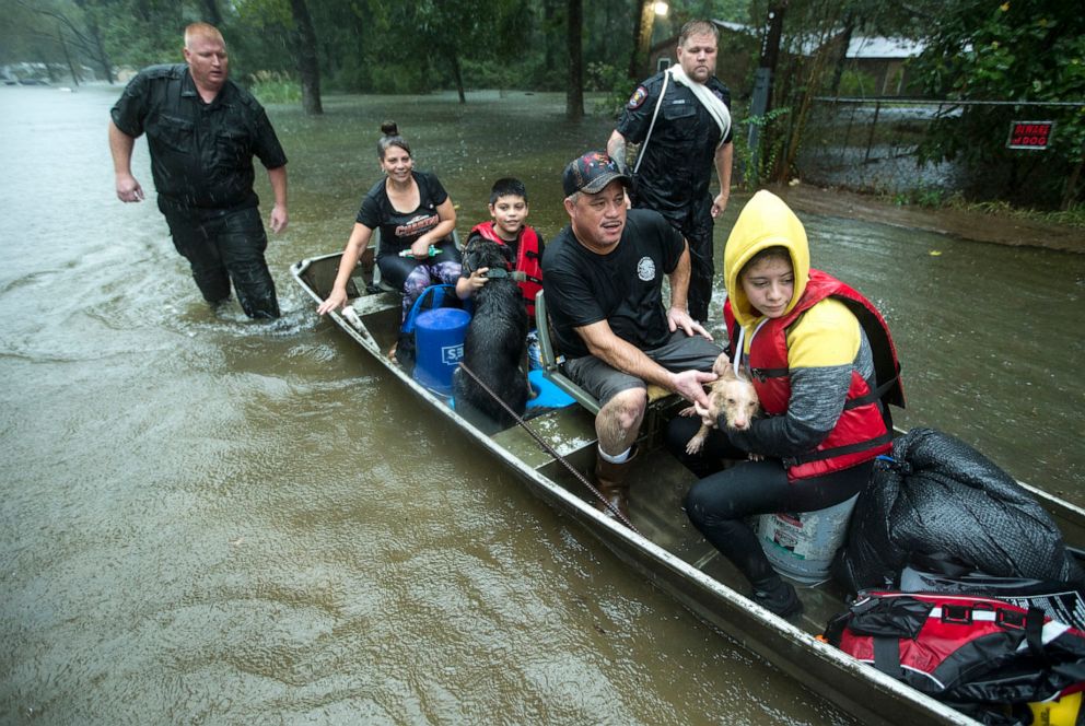 PHOTO: Police officers Lt. Troy Teller, left, and Cpl. Jacob Rutherford guide a boat carrying Maria, Ramiro, Jr., Ramiro and and Veronica Lopez from their flooded neighborhood, Sept. 19, 2019, in Spendora, Texas.