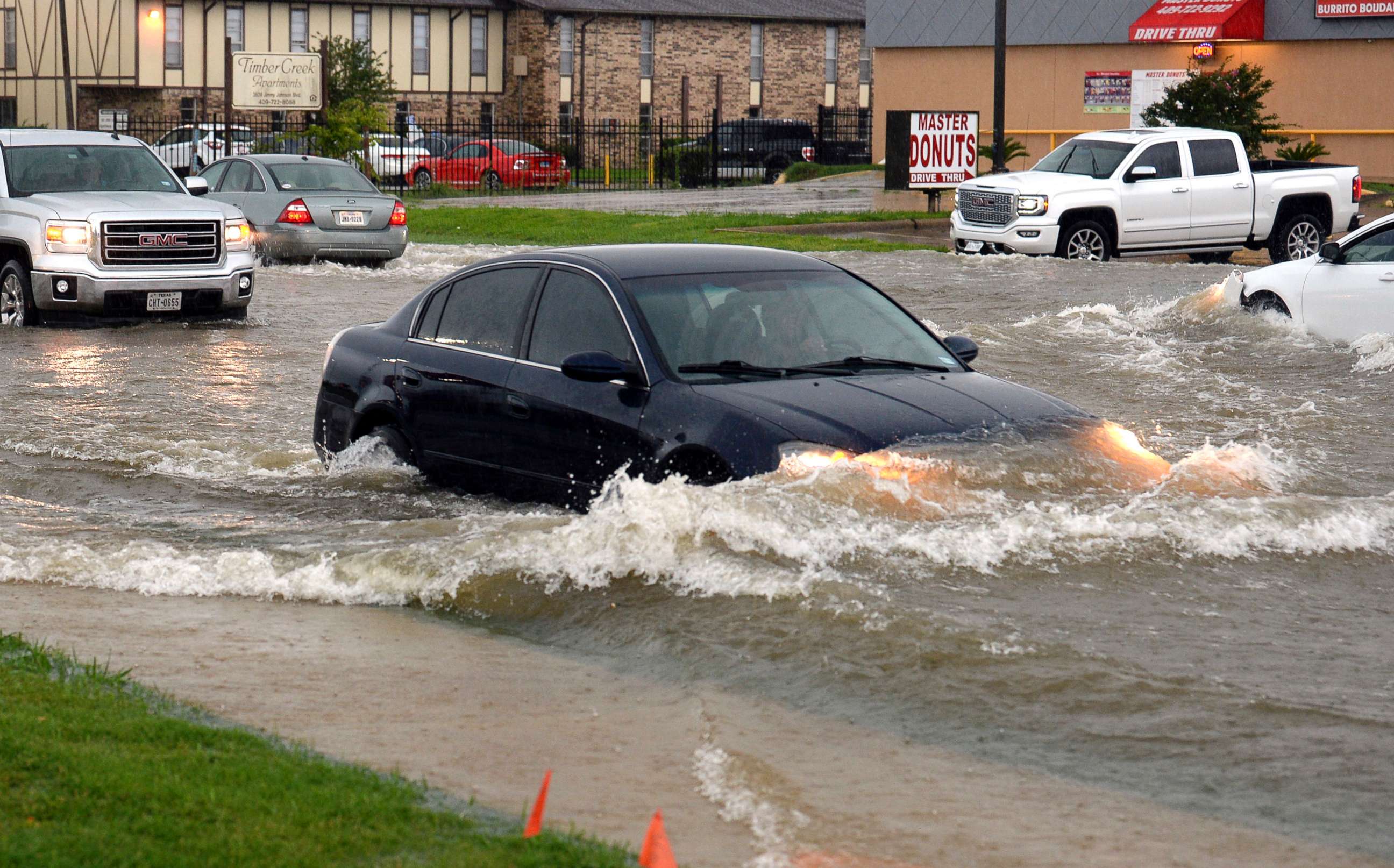 PHOTO: In this Tuesday, June 19, 2018 photo, cars push through high waters on Jimmy Johnson Boulevard during a rain storm in Port Arthur, Texas.