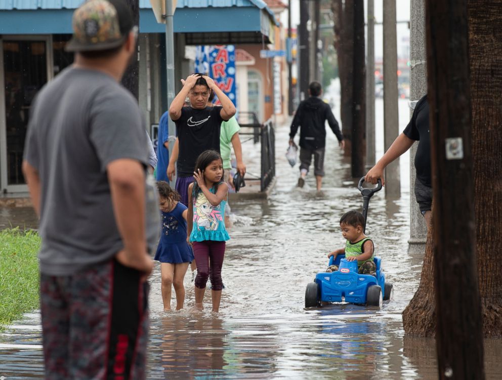 PHOTO: Area residents wade through floodwaters, June 20, 2018, on Texas Avenue in Weslaco, Texas.
