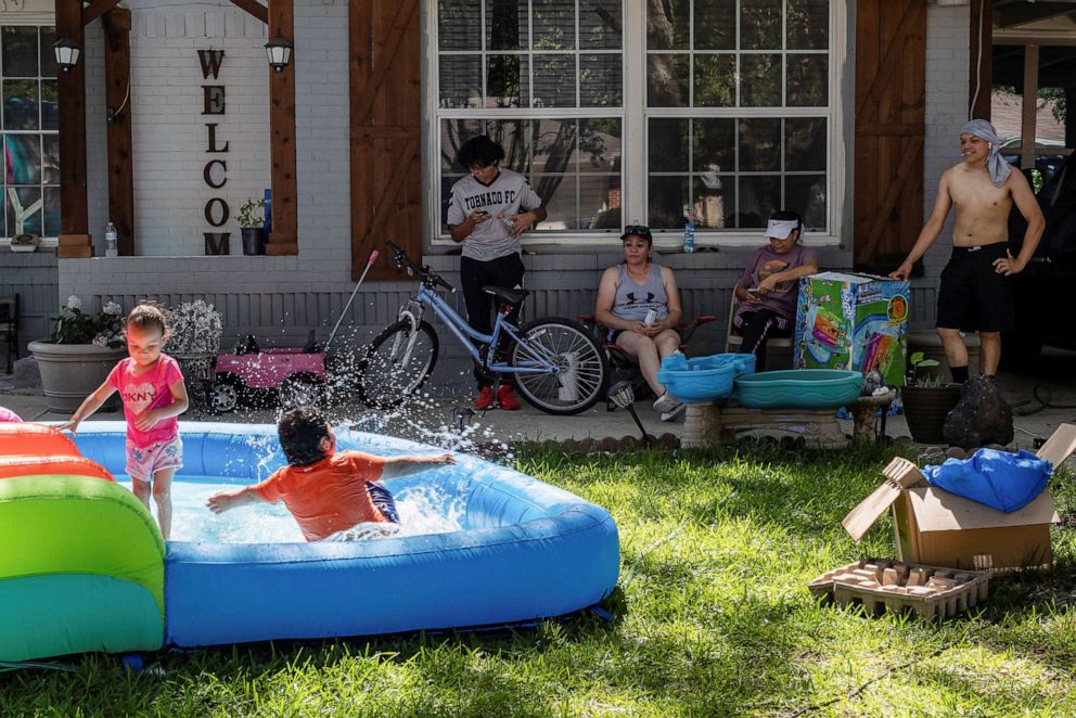 PHOTO: Neighbors Samuel Hernandez, Maria Hernandez, Luisa Ortega and Issac Montelongo sit outside as they watch the kids play during a heatwave with expected temperatures of 102 F (39 C) in Dallas, Texas, June 12, 2022.