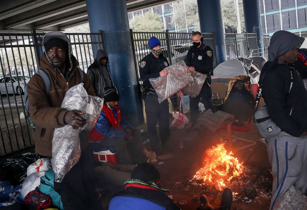 PHOTO: Police officers Kenneth Bigger, center, and Aaron Day, center right, hand out blankets to people under the elevated portion of I-45 in downtown Houston, Feb. 16, 2021.