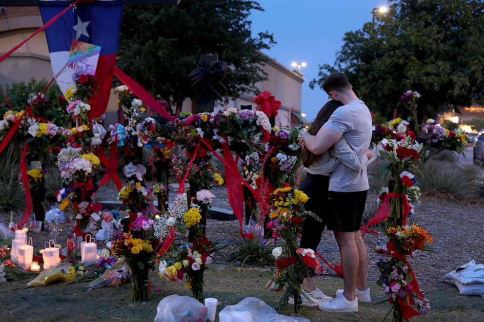 PHOTO: People hug as they visit the memorial next to the Allen Premium Outlets, May 7, 2023 in Allen, Texas.