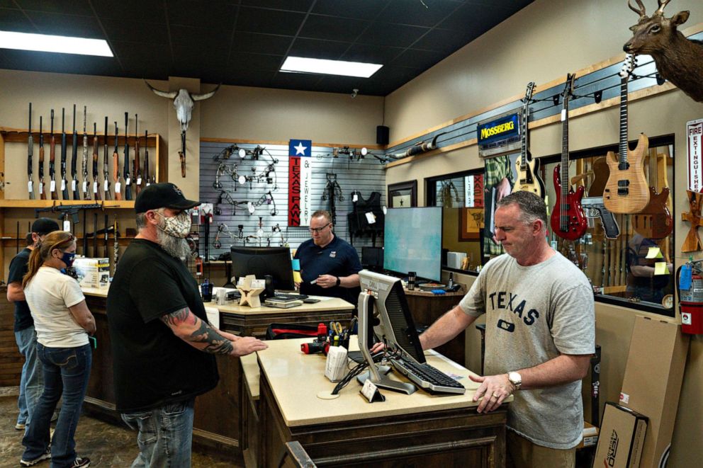 PHOTO: Customers wear masks in a pawn shop that does not require people to wear a face mask in Leander, Texas on March 3, 2021.