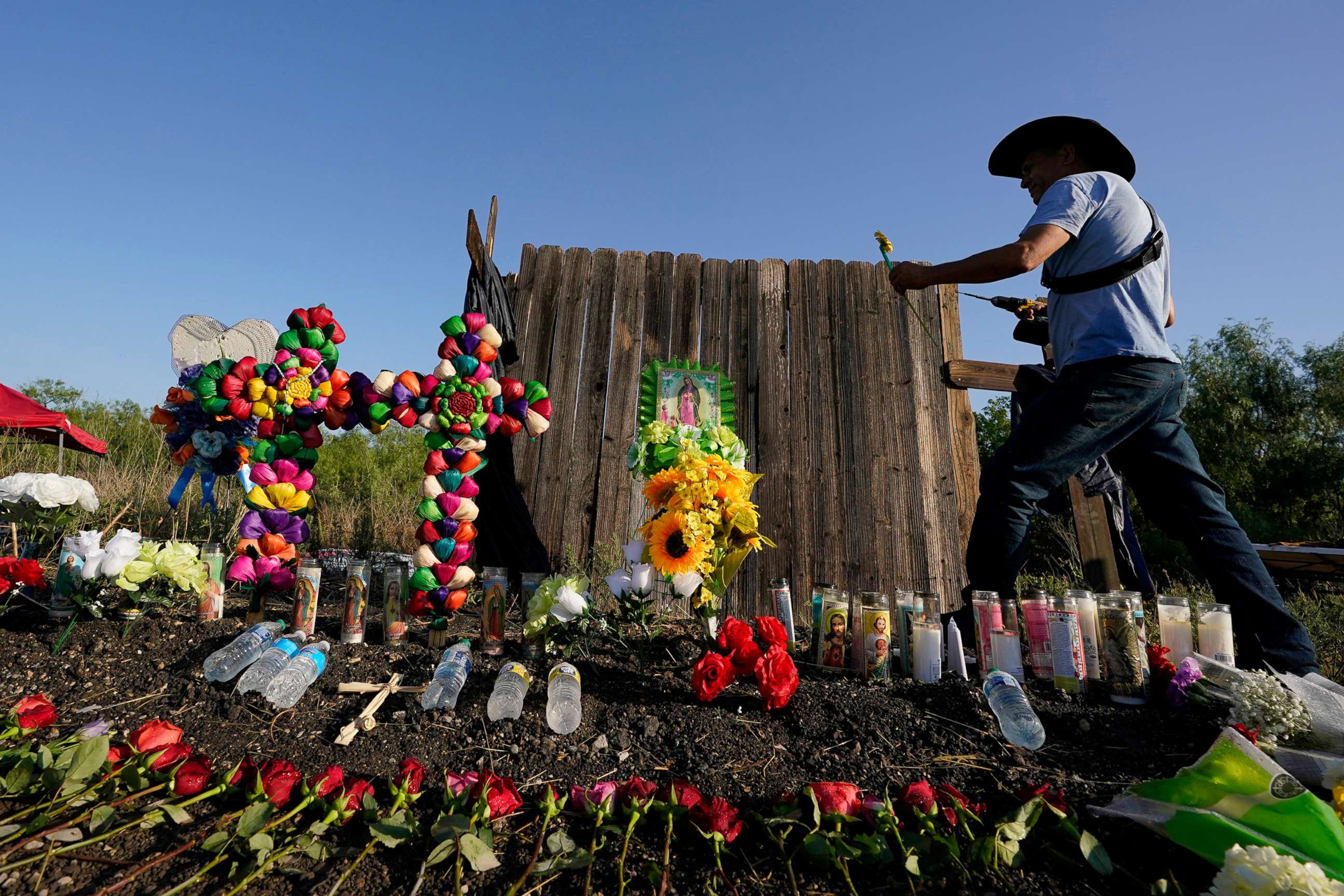 PHOTO: Roberto Marquez of Dallas adds a flower a make-shift memorial at the site where officials found dozens of people dead in an abandoned semitrailer containing suspected migrants in in San Antonio, Texas, June 29, 2022.