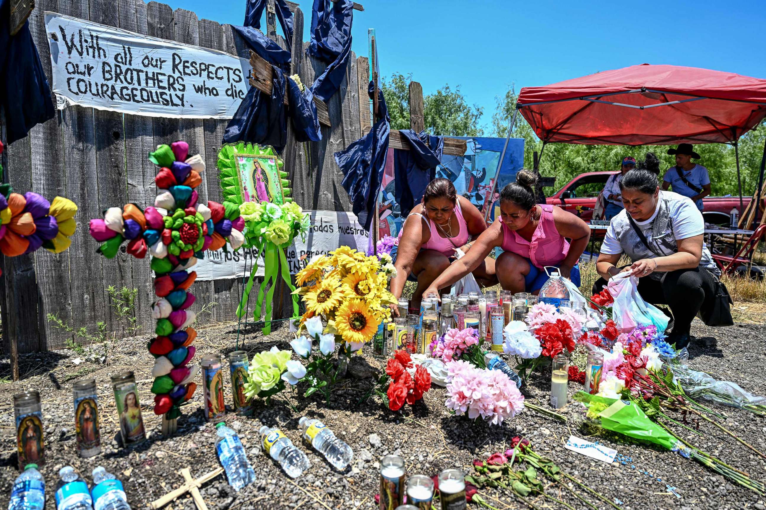 PHOTO: In this June 29, 2022, file photo, people place flowers and candles at a makeshift memorial where a tractor-trailer was discovered with deceased migrants inside, outside San Antonio, Texas.