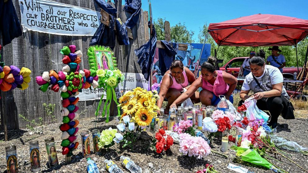 PHOTO: In this June 29, 2022, file photo, people place flowers and candles at a makeshift memorial where a tractor-trailer was discovered with deceased migrants inside, outside San Antonio, Texas.