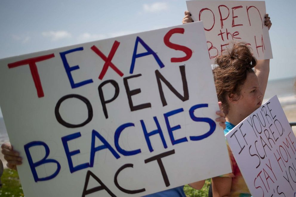 PHOTO: Local residents hold signs in protest of closed beaches on the 4th of July amid the global outbreak of the coronavirus disease in Galveston, Texas, July 4, 2020.